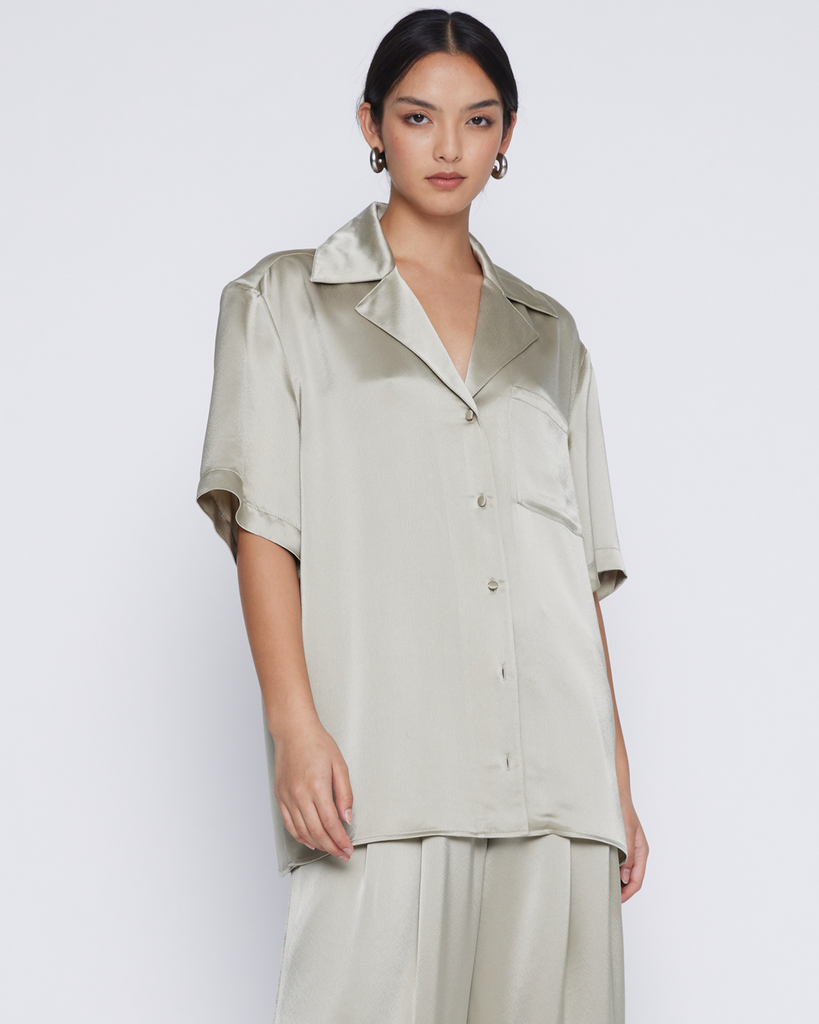 A relaxed unisex fit allowing creativity to style any way you choose. This fluid shirt is cut in a Japanese satin acetate made special with its soft drape and muted taupe hue. Designed with a boxy shoulder, camper collar, breast pocket, and back y By Anna Quan, now available at After Eight. 
