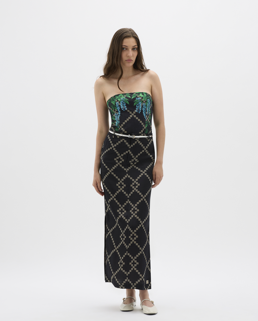 Created in a lustrous, silky blend with a Muma signature logo designs, the skirt is a specialty piece pairing with the Jade Vine Bandeau. Expertly crafted in vegan cupro, this structured skirt buttons at the front and splits at the back, flowing down an elongated hemline to the ankles, meeting embroidered logo detailing. Simultaneously elegant and relaxed, the style allows for movement, festivity, and indulgence all around. By Muma World, now available at After Eight. 