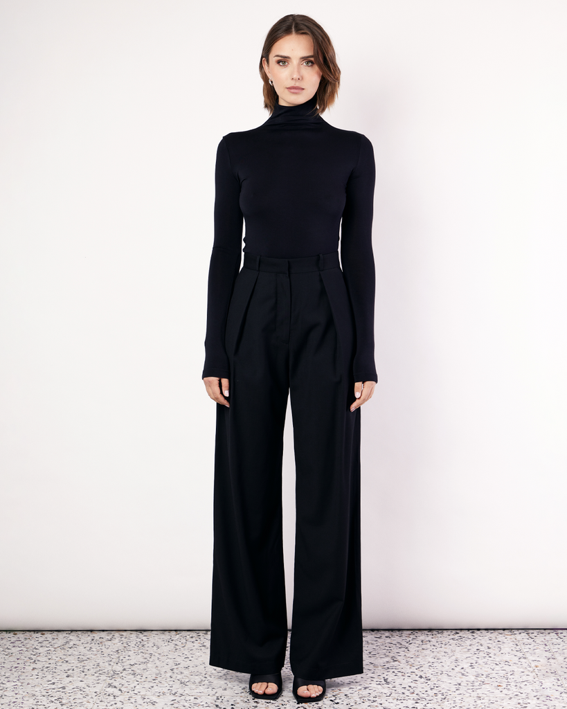The Pleat Front Pant are an easy-wearing wide leg pant featuring a hidden clasp closure, pockets, and pleated detailing down the front, creating a subtle drape in the leg. They are crafted from a soft wool blend in Black. By Romy, now available at After Eight. 
