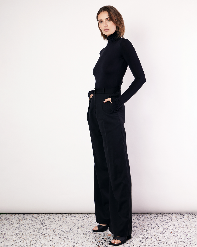 The Pleat Front Pant are an easy-wearing wide leg pant featuring a hidden clasp closure, pockets, and pleated detailing down the front, creating a subtle drape in the leg. They are crafted from a soft wool blend in Black. By Romy, now available at After Eight. 