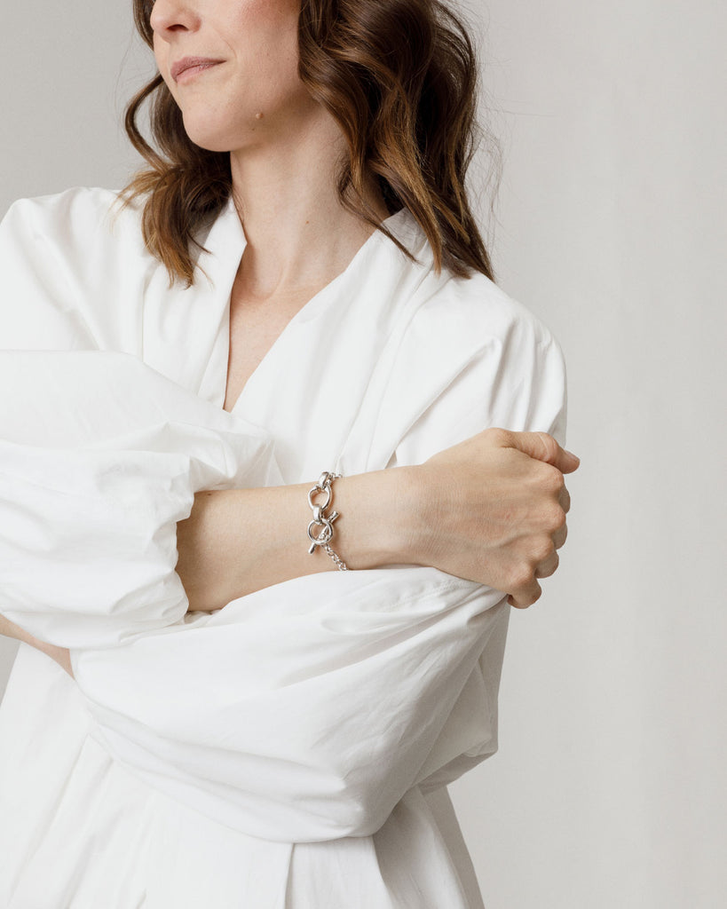 The Mother Jug Fob bracelet is a silky rolo chain attached to a fluid, wave like t-bar and Mineraleir's signature mother jug chain links, made from recycled sterling silver plated with Rhodium. By sustainable Australian brand Mineraleir.