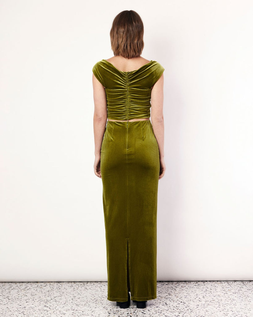 The Velvet Top exudes elegance and lust featuring ruched detailing, an off the shoulder neckline, and a cropped length. It is crafted from a plush stretch Velvet fabrication in a stunning green hue. By Romy, now available at After Eight. 