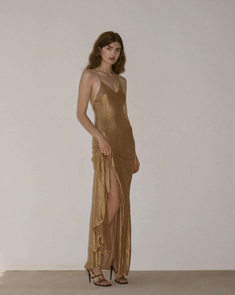 The Milou Slip Dress is crafted from a viscose jersey in a laminated gold. It features a full length silhouette, with a V neck and slightly flared skirt. By Auteur, now available at After Eight. 