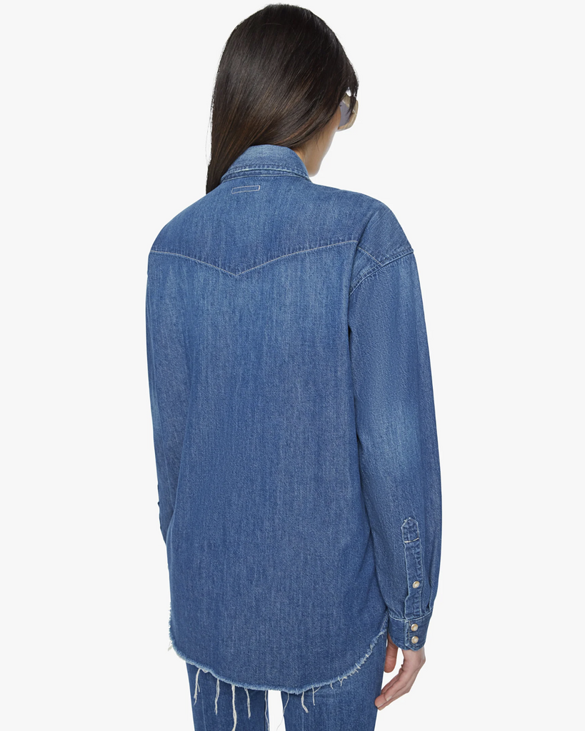 An oversized Western-inspired denim button-up with front patch pockets and a raw, curved hem. Made from 100% cotton, Dopenhagen is a vintage-blue wash with subtle fading throughout. By Mother Denim, now available at After Eight. 