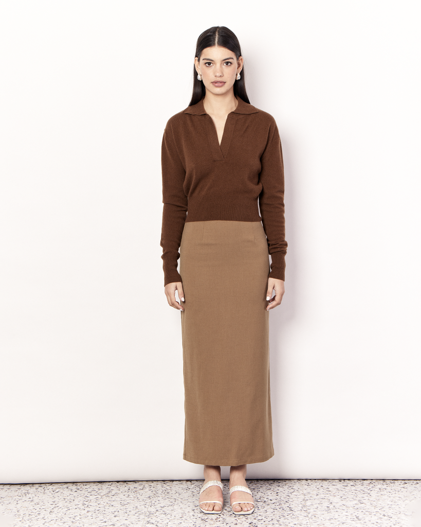 The Cropped Collared Sweater is a trans-seasonal knitwear essential, featuring a collar, deep-v neckline, and cropped hem. It is crafted from a luxurious Wool Cashmere blend in an Olive Brown hue. By Romy, now available at After Eight. 