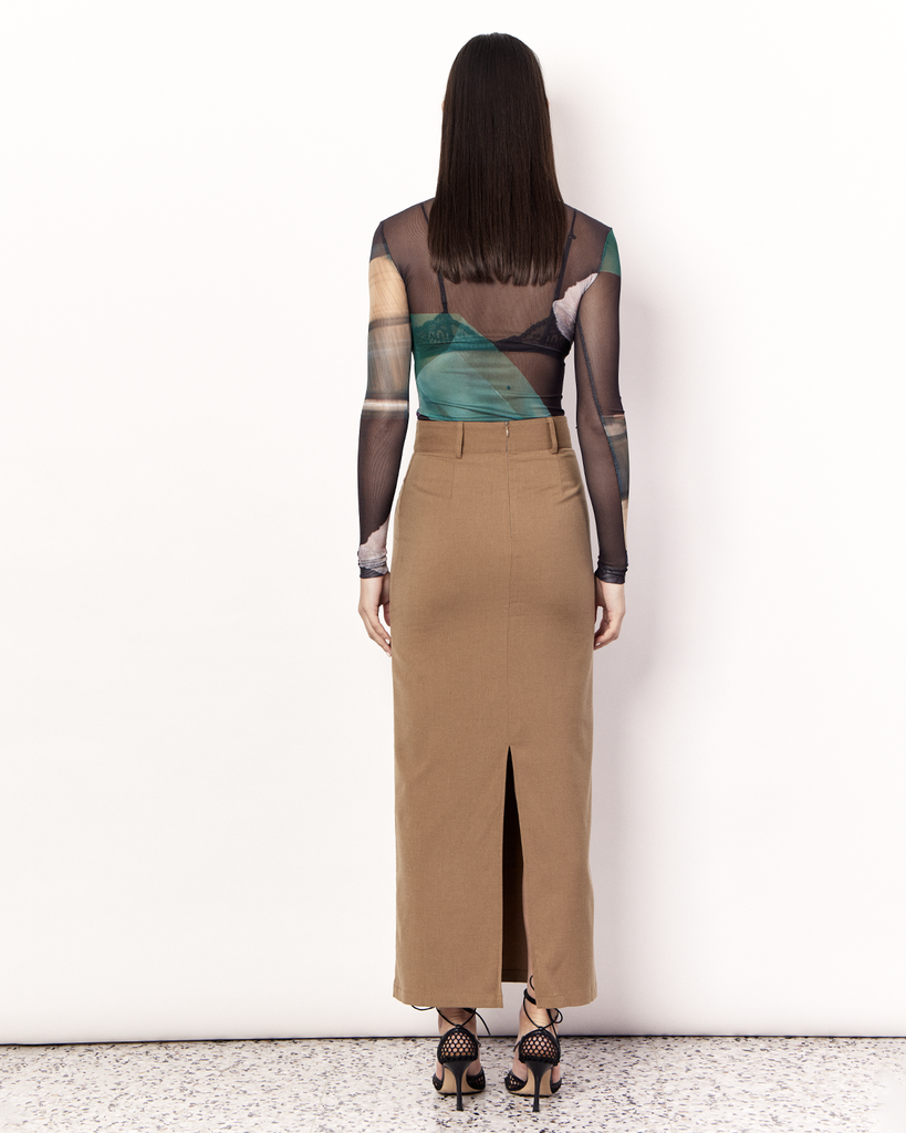 The Maxi Suiting Skirt is a tailored skirt to take you from desk to dinner with ease, featuring belt loops and a back split for ease of wear. It is crafted from a soft wool blend in Tan. By Romy, now available at After Eight. 