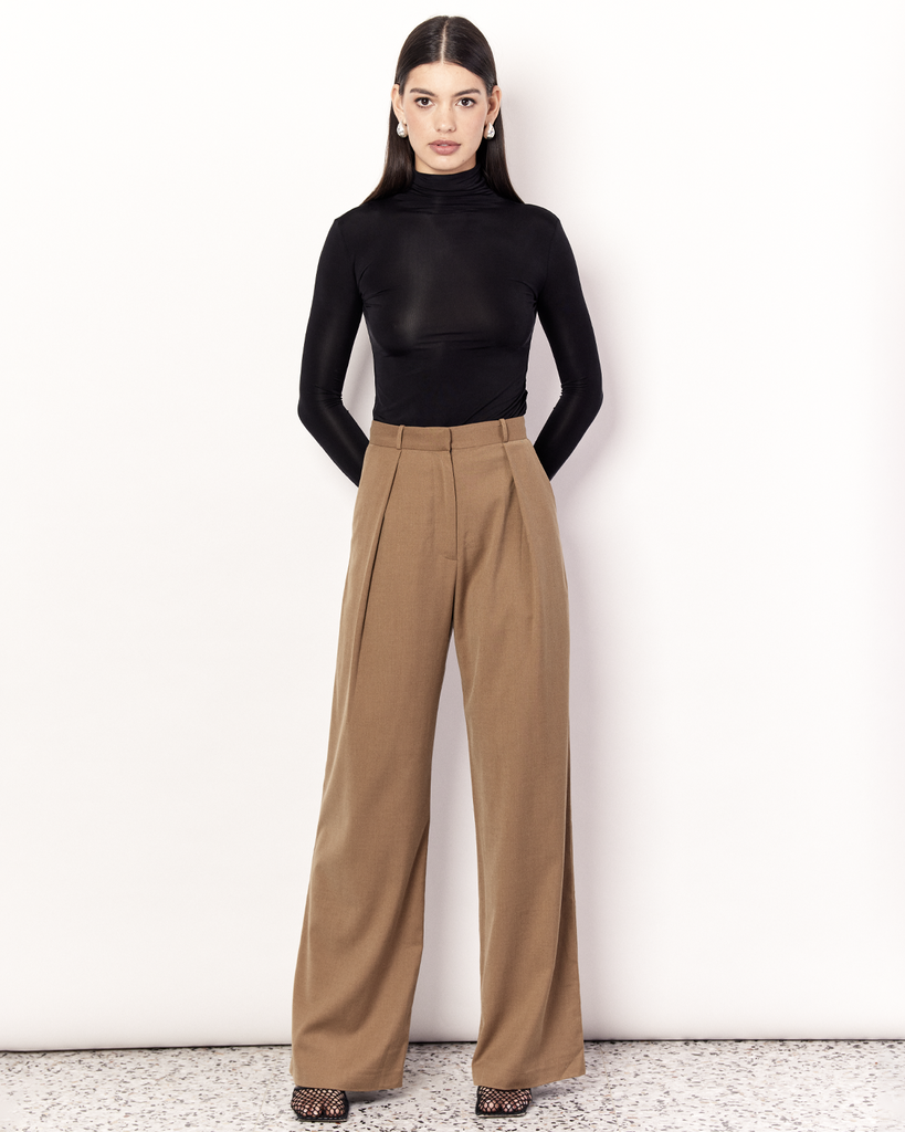 The Pleat Front Pant are an easy-wearing wide leg pant featuring a hidden clasp closure, pockets, and pleated detailing down the front, creating a subtle drape in the leg. They are crafted from a soft wool blend in Tan. By Romy, now available at After Eight. 