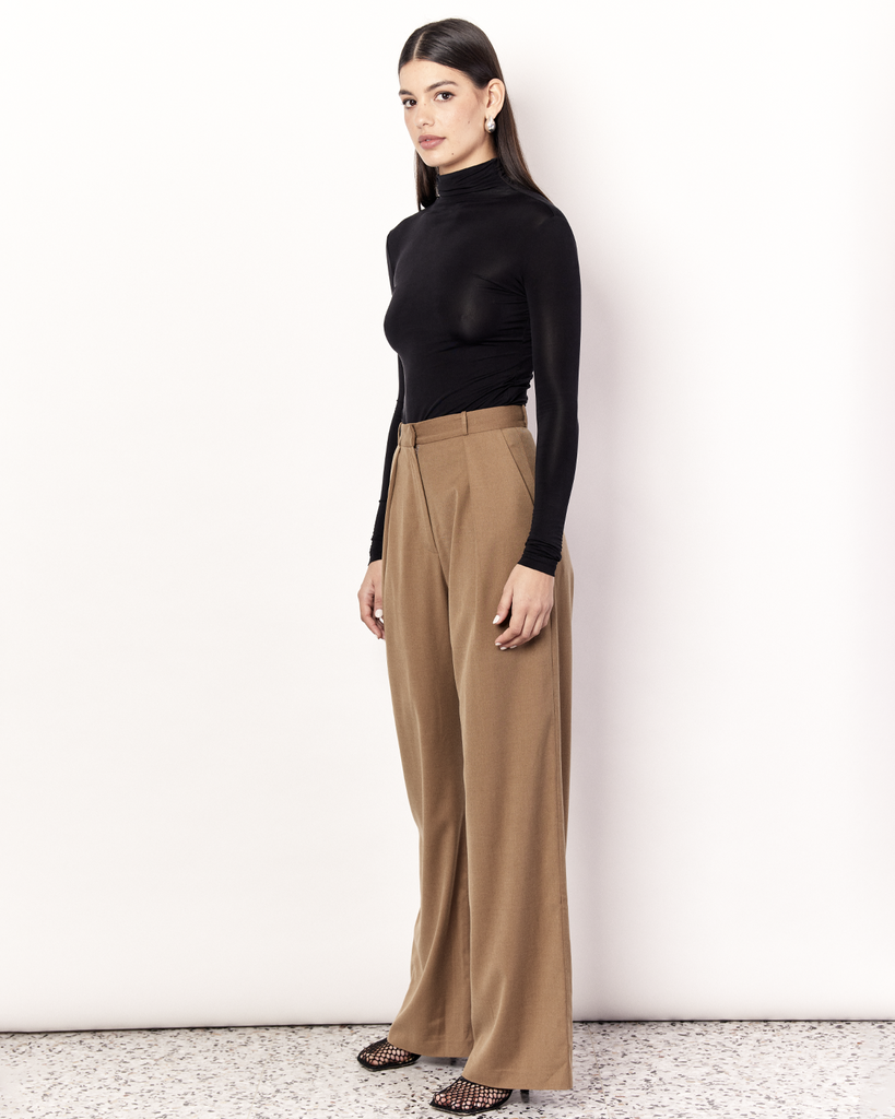 The Pleat Front Pant are an easy-wearing wide leg pant featuring a hidden clasp closure, pockets, and pleated detailing down the front, creating a subtle drape in the leg. They are crafted from a soft wool blend in Tan. By Romy, now available at After Eight. 