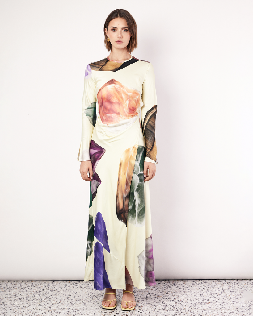The Gemstone Wrap Dress boasts a fluid form and elevated style, featuring gathered detailing and a leg split. It is crafted from a silky recycled Oeko-Tex® certified viscose in the Gemstone Print, designed exclusively for Romy. By Romy, now available at After Eight. 