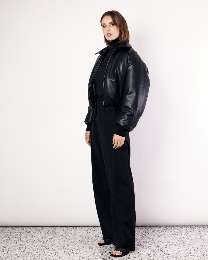 A must-have in your winter wardrobe, featuring a collar, gathered hem, and ribbed knit cuffs. It is crafted from a buttery soft Vegan Leather in Black. By Romy, now available at After Eight. 