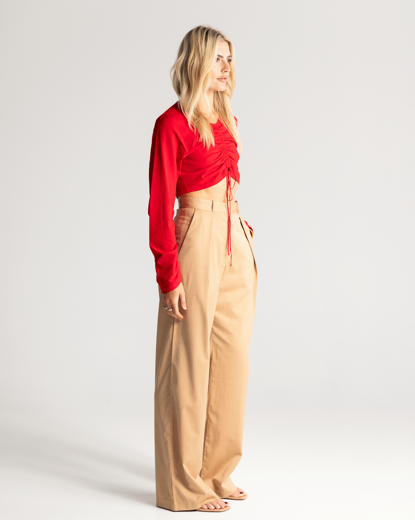 The Tie Front Top is crafted from a soft crepe knit in a vibrant red hue. It is a cropped style and features a drawstring tie through the centre front giving it an elevated look.  *Pleat Front Pant coming soon. By Romy, now available at After Eight.