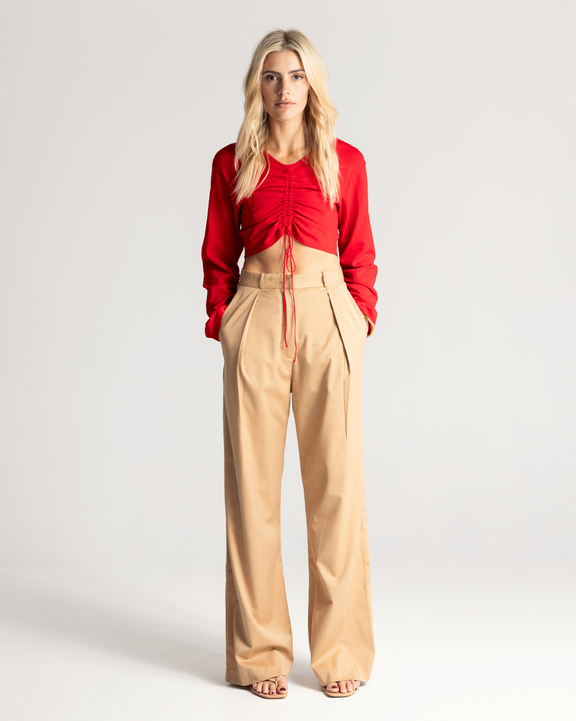 The Tie Front Top is crafted from a soft crepe knit in a vibrant red hue. It is a cropped style and features a drawstring tie through the centre front giving it an elevated look.  *Pleat Front Pant coming soon. By Romy, now available at After Eight.