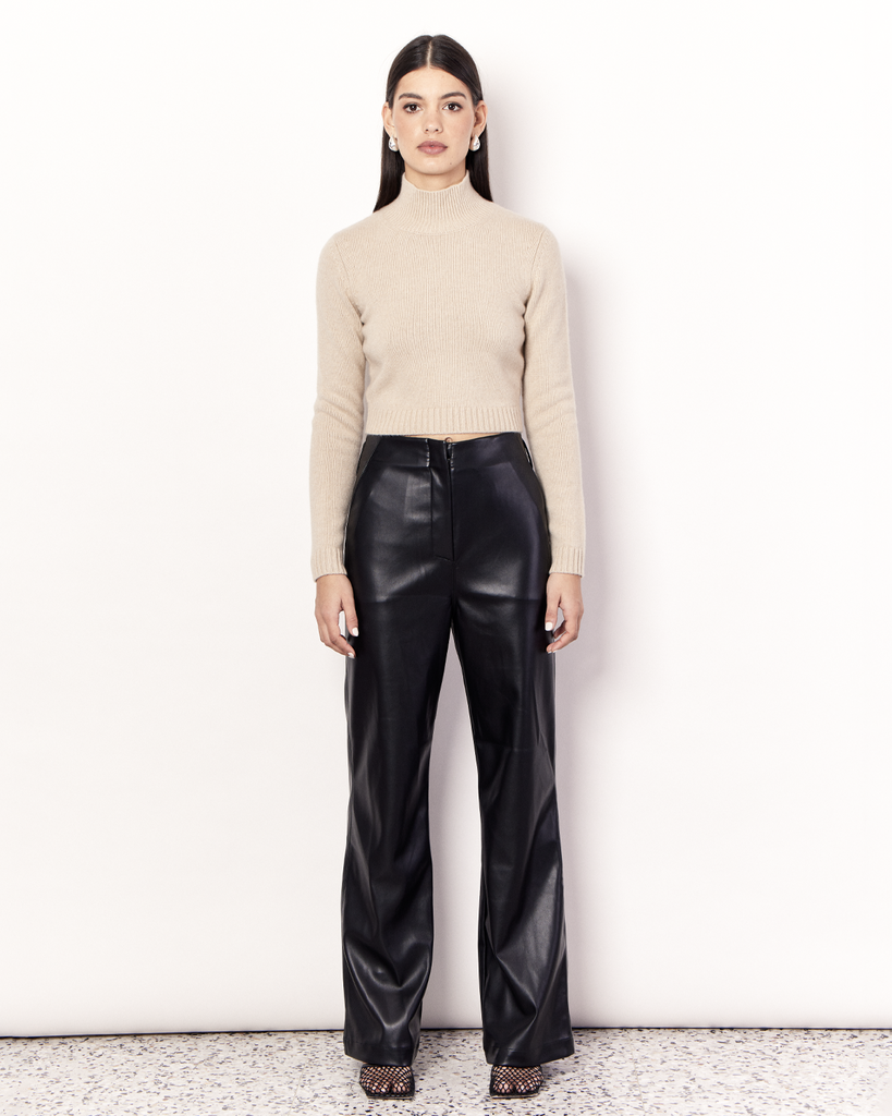 The Cropped Funnel Neck Sweater is a lightweight knitwear essential that hugs the body, featuring a funnelneck and cropped hemline. It is crafted from a luxurious Wool Cashmere Blend in a neutral Sand hue. By Romy, now available at After Eight. 