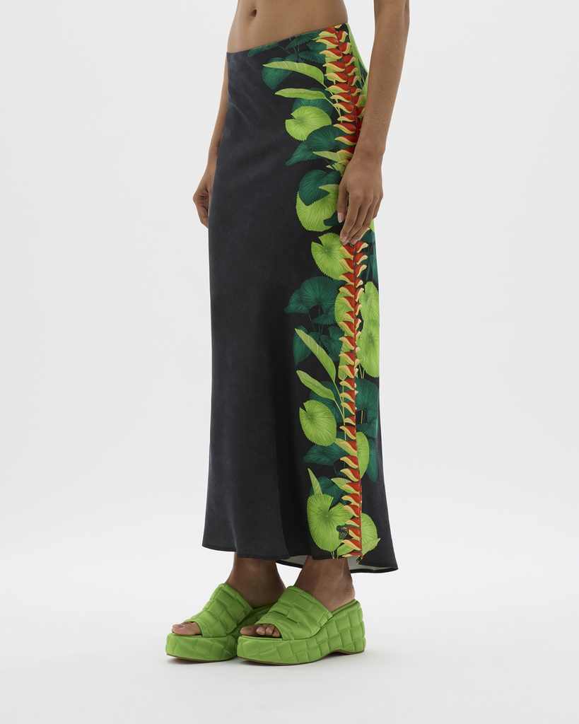 Created in a lustrous, silky vegan cupro with a Muma hand-illustrated and hand-placed Lobster Claw Flowers Leaves from the region in-focus. OK Marine Biodegradable Certified Cupro drapes like silk and this bias-cut maxi skirt flows down an elongated hemline to the ankles, meeting embroidered logo detailing. Simultaneously elegant and relaxed, the high-rise, thick-band elastication around the waist allows for movement, festivity, and indulgence all around. By Muma World, now available at After Eight. 