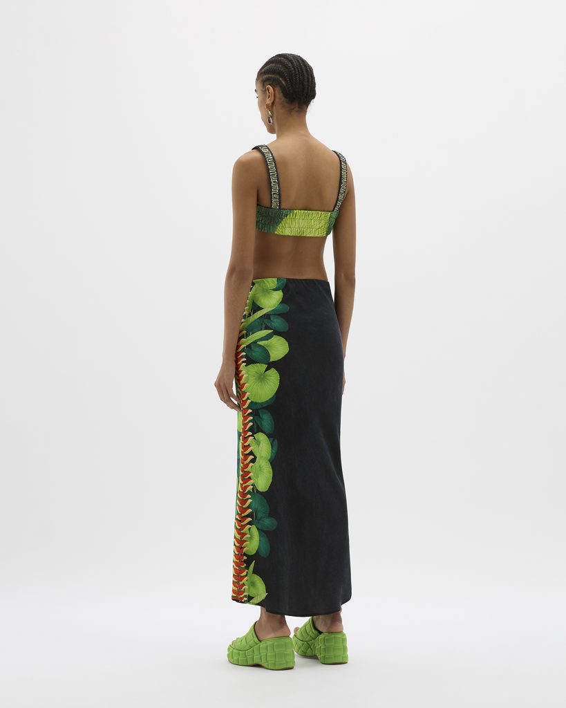 Created in a lustrous, silky vegan cupro with a Muma hand-illustrated and hand-placed Lobster Claw Flowers Leaves from the region in-focus. OK Marine Biodegradable Certified Cupro drapes like silk and this bias-cut maxi skirt flows down an elongated hemline to the ankles, meeting embroidered logo detailing. Simultaneously elegant and relaxed, the high-rise, thick-band elastication around the waist allows for movement, festivity, and indulgence all around. By Muma World, now available at After Eight. 