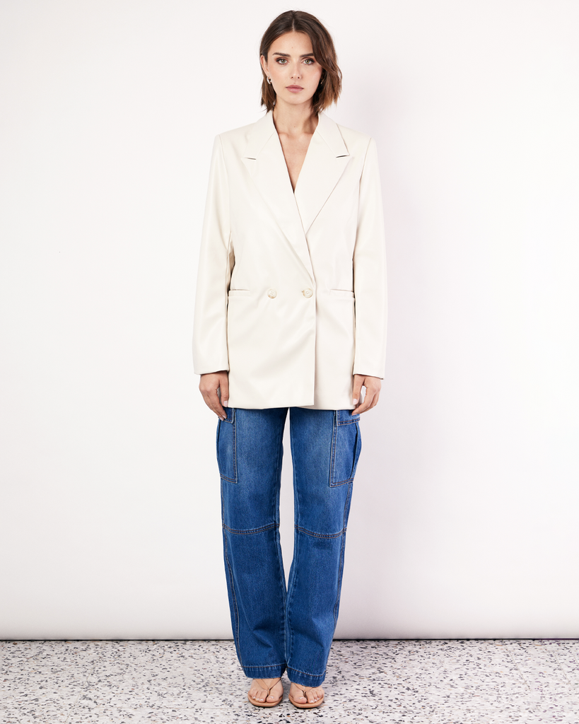 The Vegan Leather Boxy Blazer is a relaxed, oversized silhouette, featuring front pockets and a button closure. It is fully lined and is crafted from a buttery soft Vegan leather fabrication in Cream. By Romy, now available at After Eight. 