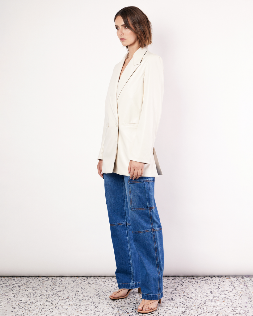 The Vegan Leather Boxy Blazer is a relaxed, oversized silhouette, featuring front pockets and a button closure. It is fully lined and is crafted from a buttery soft Vegan leather fabrication in Cream. By Romy, now available at After Eight. 