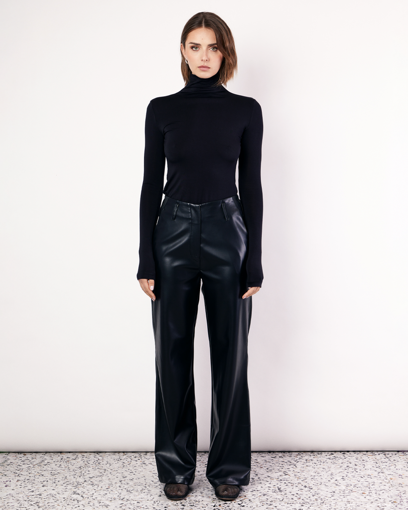 The Vegan Leather Pant are a mid-rise straight leg pant, featuring pockets, belt loops and a hidden clasp closure. They are crafted from a buttery soft Vegan Leather fabrication in Black. By Romy, now available at After Eight. 