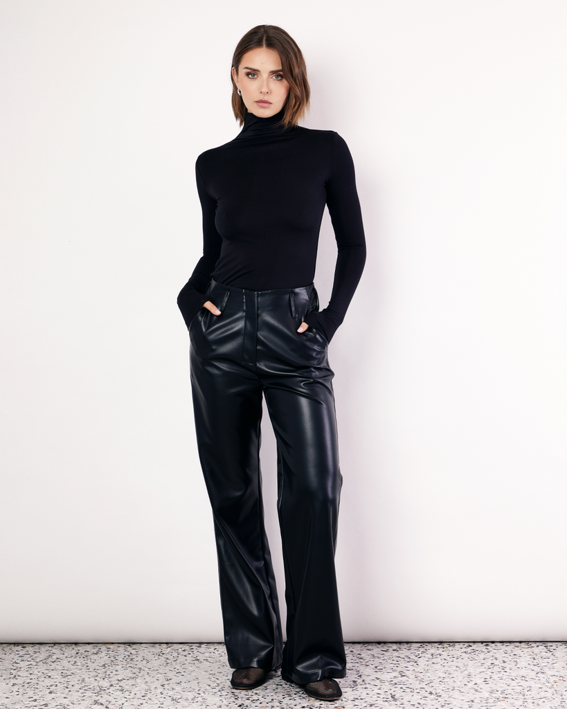 The Vegan Leather Pant are a mid-rise straight leg pant, featuring pockets, belt loops and a hidden clasp closure. They are crafted from a buttery soft Vegan Leather fabrication in Black. By Romy, now available at After Eight. 