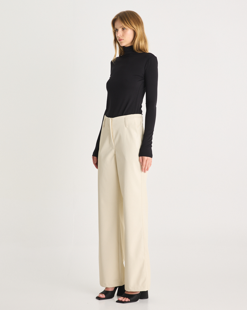 The Vegan Leather Pant are a mid-rise straight leg pant, featuring pockets, belt loops and a hidden clasp closure. They are crafted from a buttery soft Vegan Leather fabrication in Cream. By Romy, now available at After Eight. 
