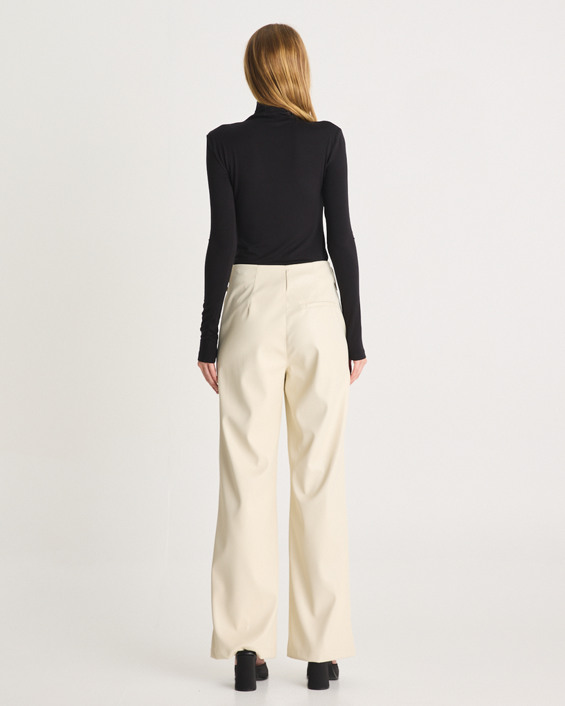 The Vegan Leather Pant are a mid-rise straight leg pant, featuring pockets, belt loops and a hidden clasp closure. They are crafted from a buttery soft Vegan Leather fabrication in Cream. By Romy, now available at After Eight. 