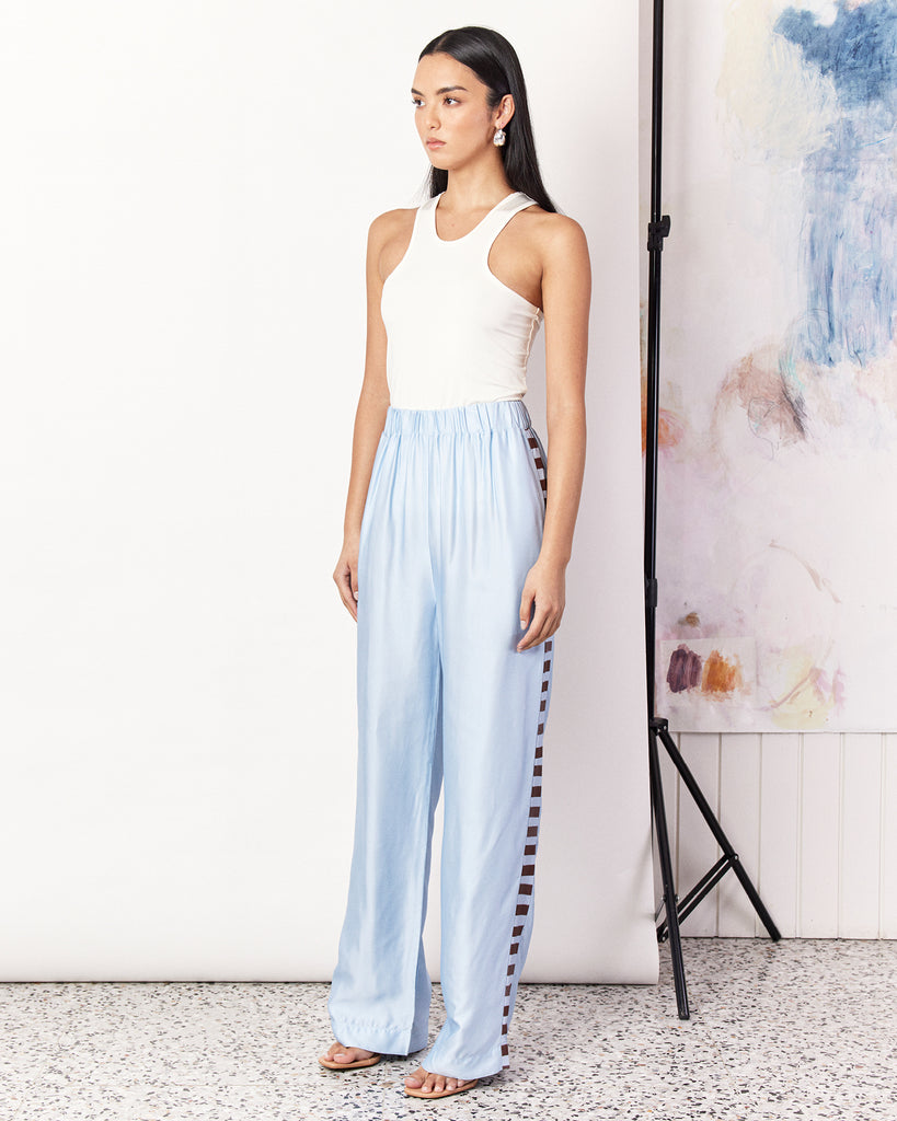 The Waterfront Pant is a relaxed style straight leg pant in a sky-blue colourway detailed with the Romy exclusive waterfront print. Crafted with a silky recycled viscose blend, the pants are slightly tailored, featuring an elastic waist band and side pockets with a matte finish. Pair with the matching Waterfront Shirt to complete the set. By Romy, now available at After Eight. 