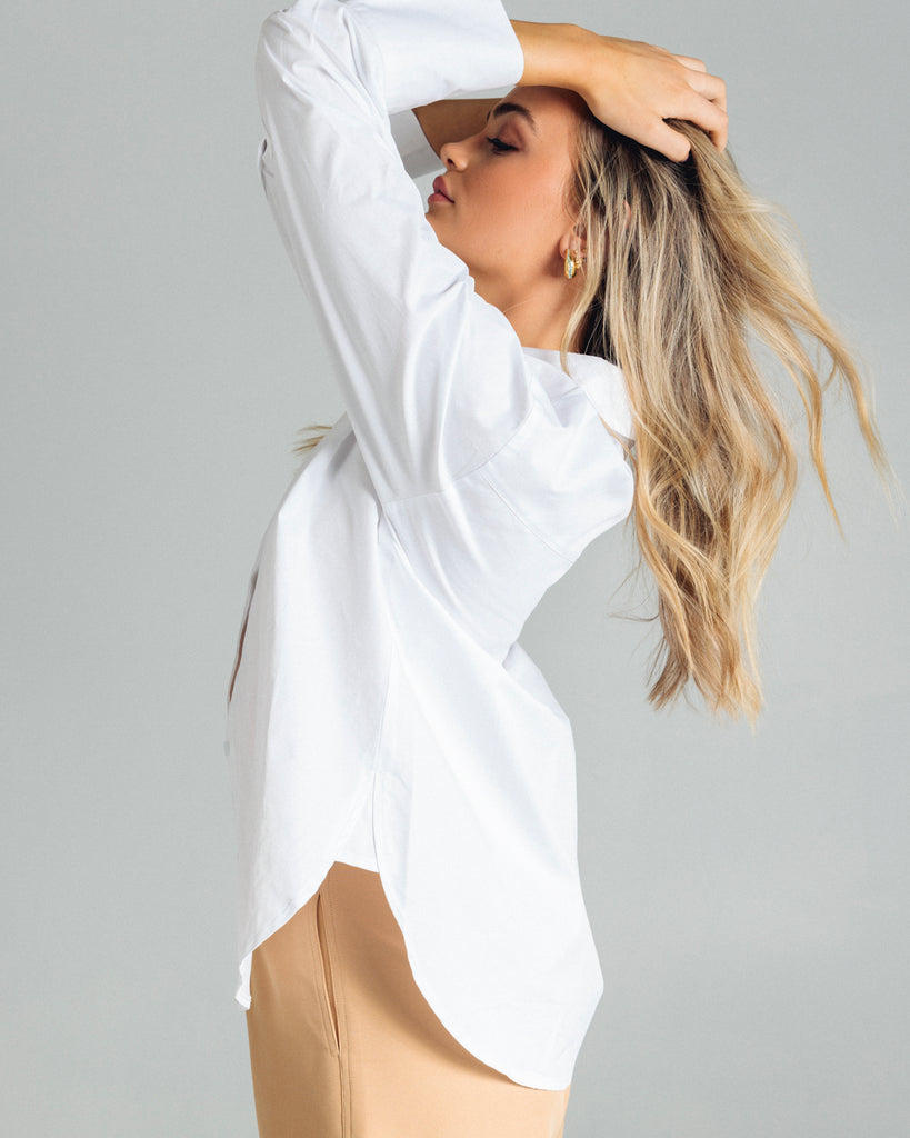 The Cotton Shirt in White has elongated cuffs and a scooped hemline. By Romy, now available at After Eight. 