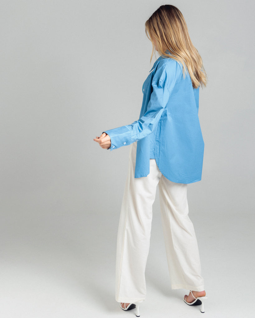 The Cotton Shirt in blue has elongated cuffs and a scooped hemline. By Romy, now available at After Eight. 