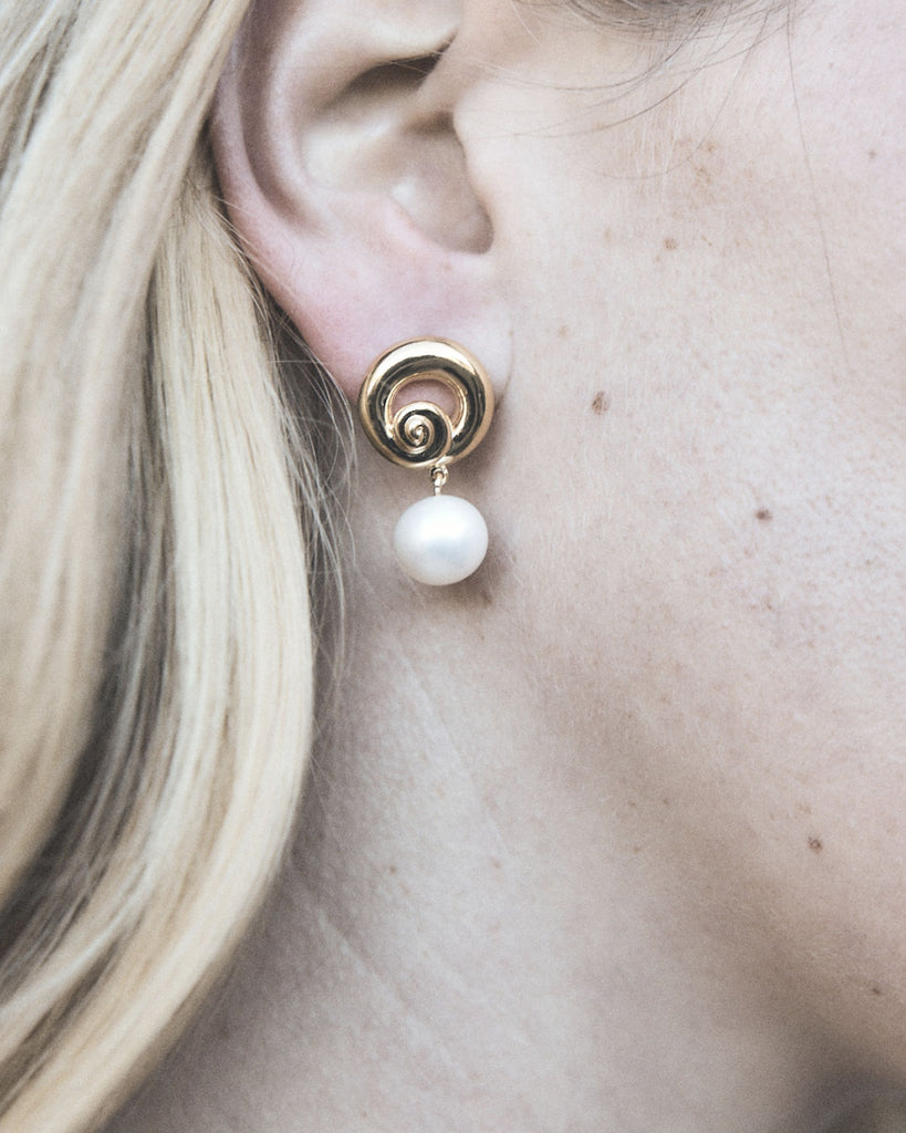 Pendulous white freshwater pearls, hung from a solid swirl stud. By Mineraleir, now available at After Eight. 